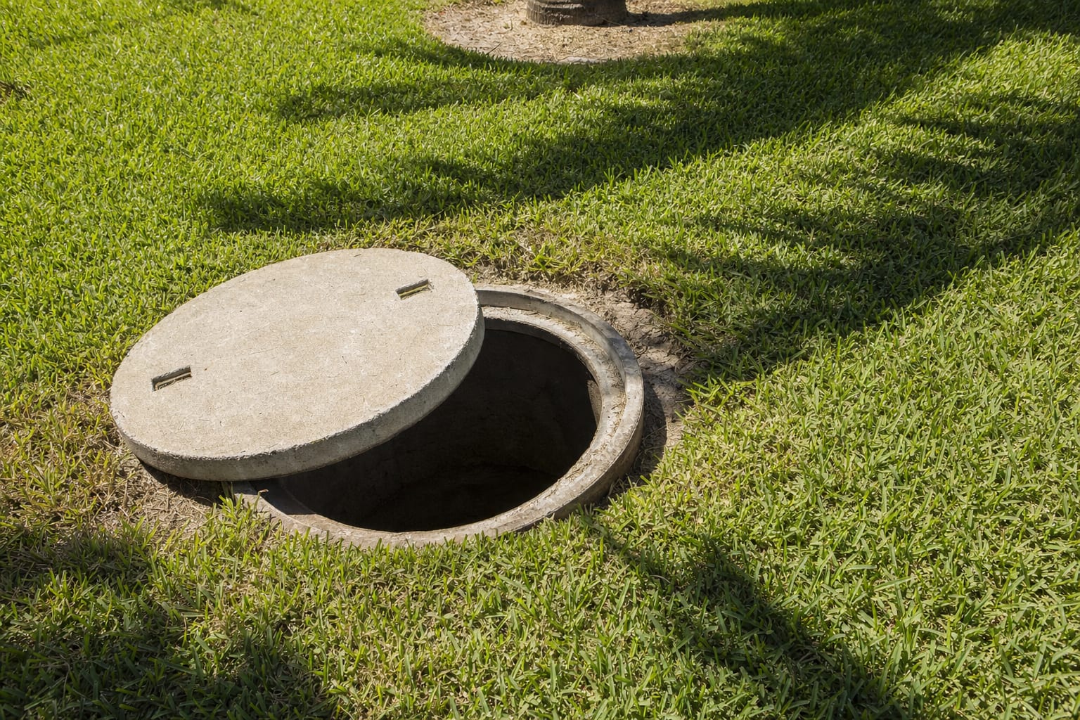 Open septic tank access lid in a Cape Coral lawn